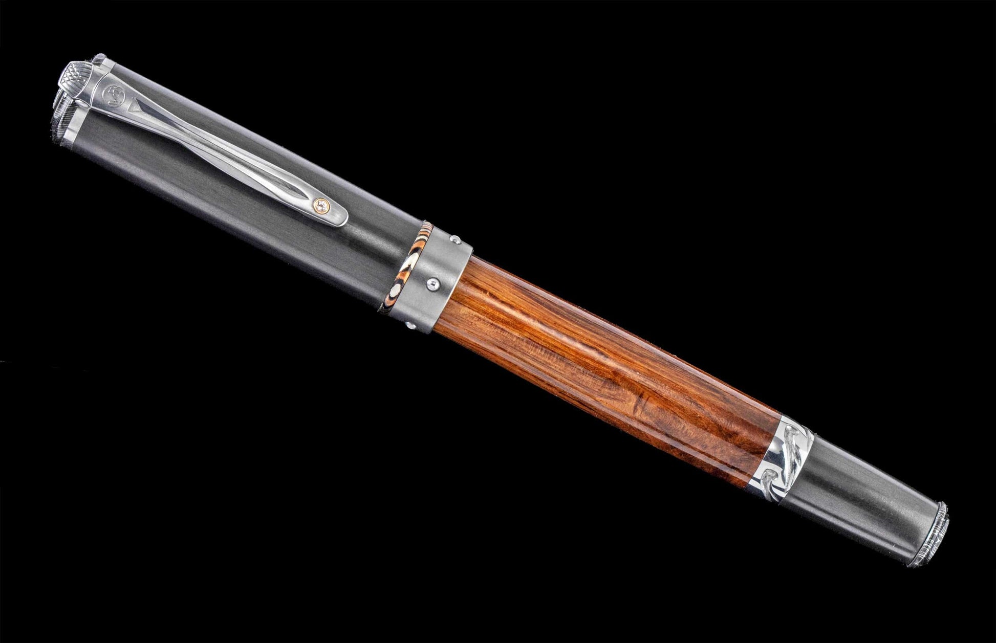 Handcrafted William Henry pen features wood from the famed HMS Victory, mokume accents, carbon fiber, and titanium set with a white topaz gemstone. 