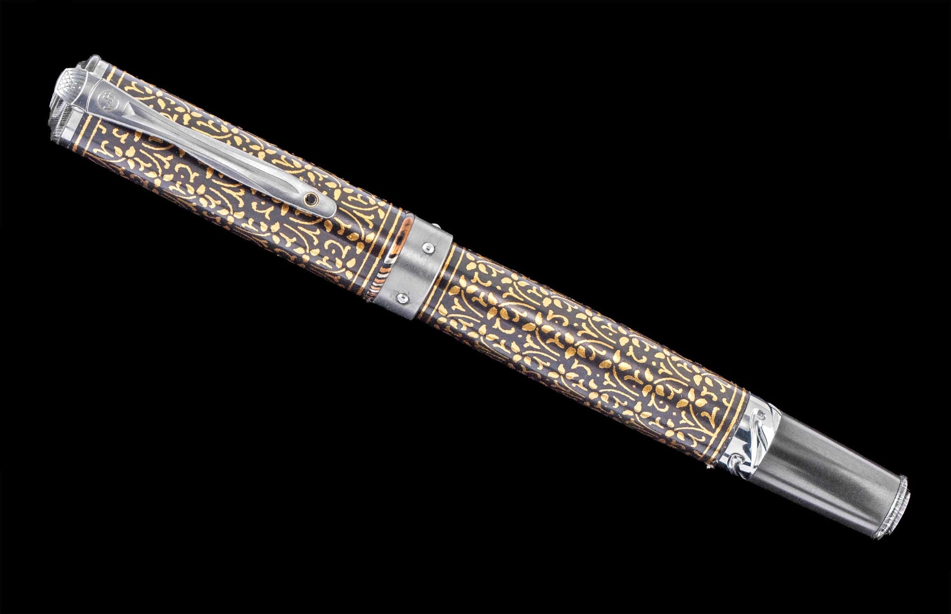 Handcrafted William Henry pen with 24K gold koftgari, titanium, and carbon fiber, with hand-forged damascus accents and a spinel gemstone.